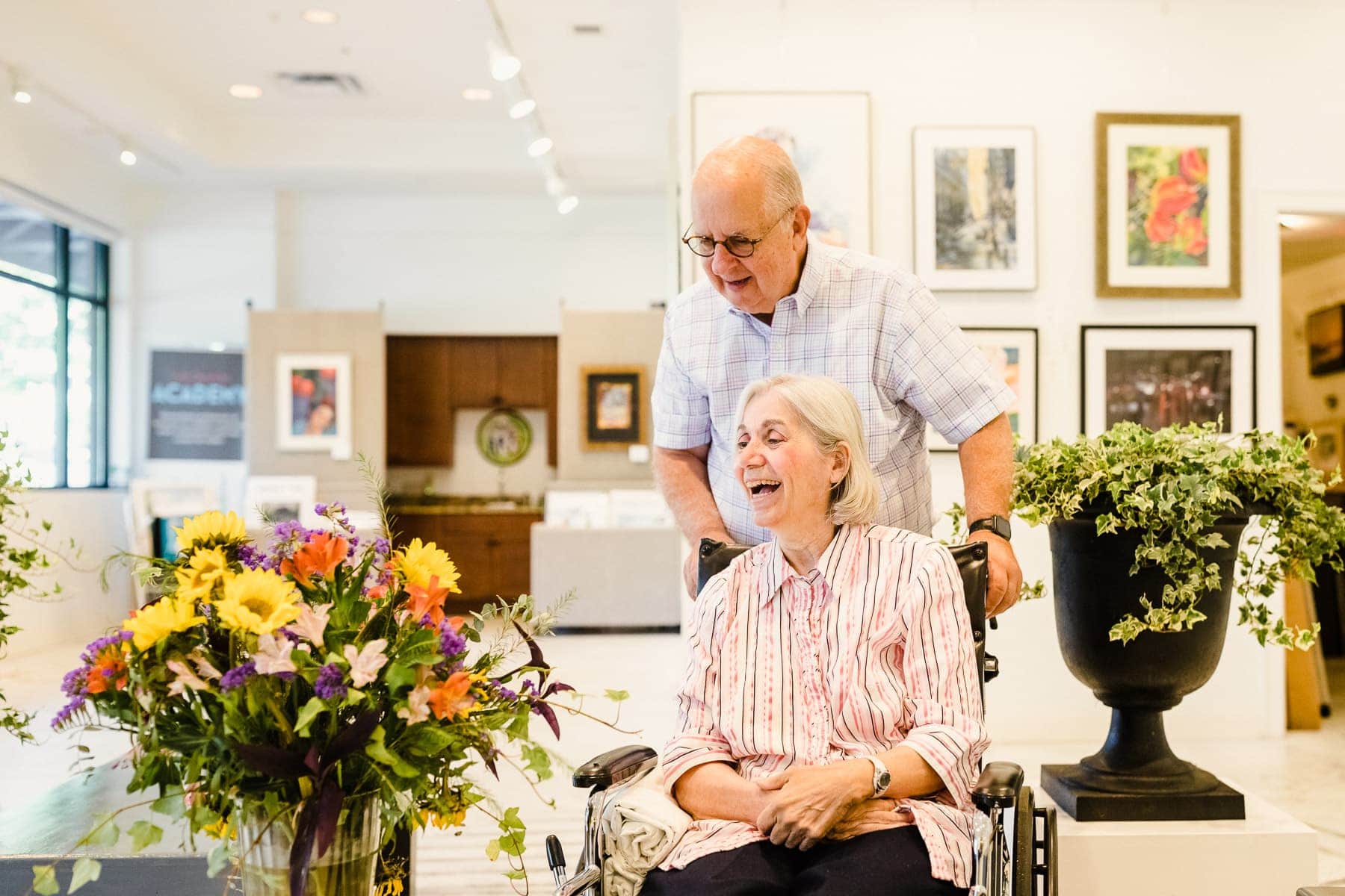 elderly couple smiling at flowers in art gallery