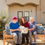 woman and elderly residents sitting on bench with dog