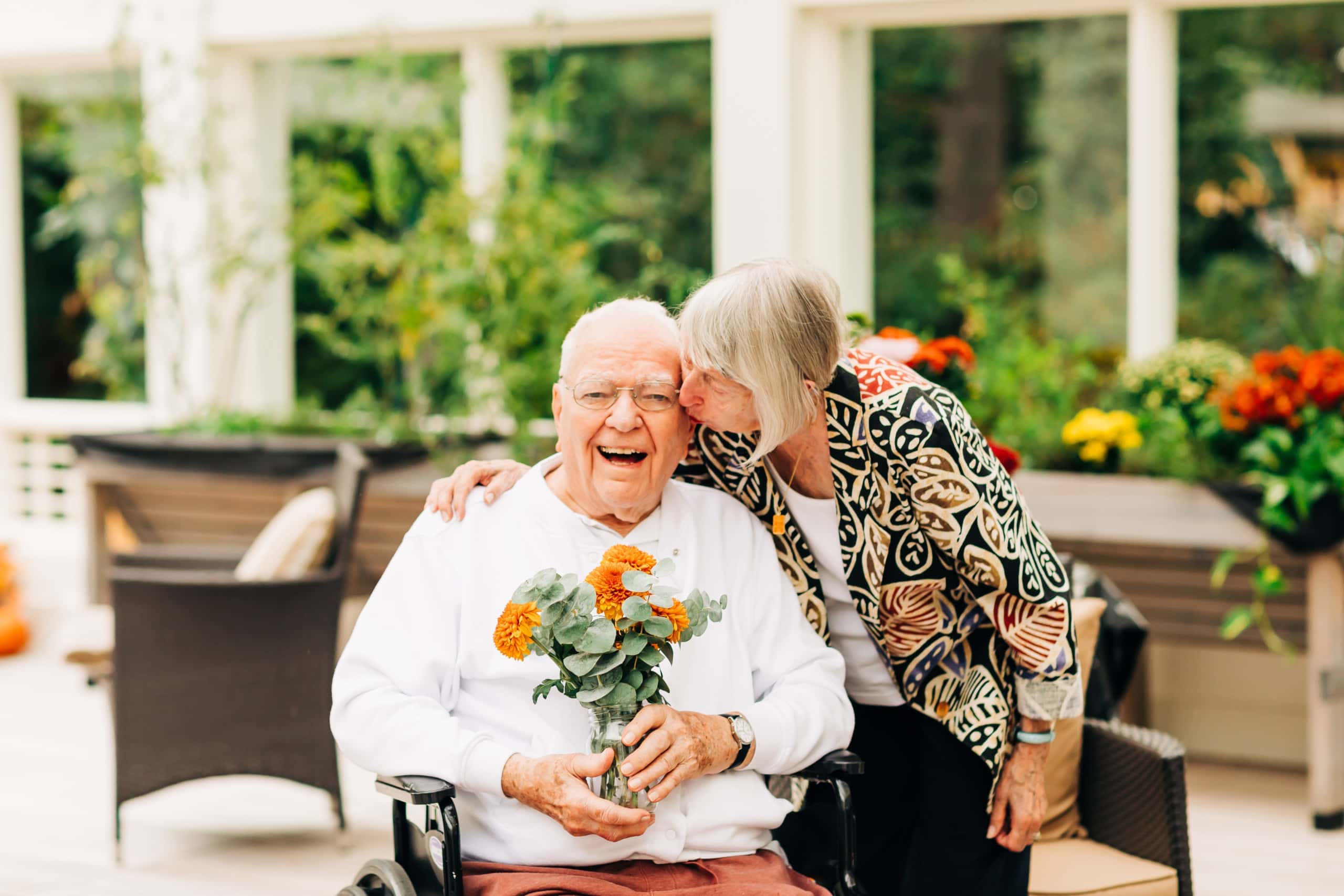 elderly couple holding flowers and kissing