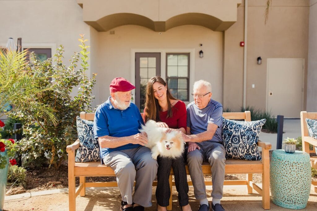 woman and elderly residents sitting on bench with dog