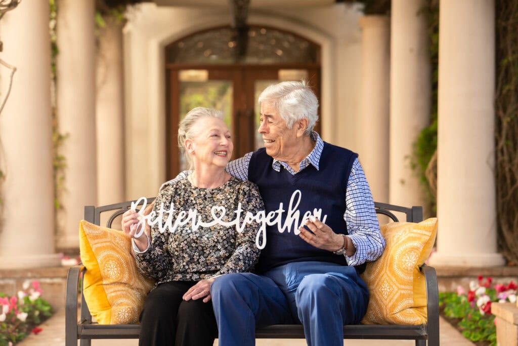 older couple smiling and holding sign that says better together