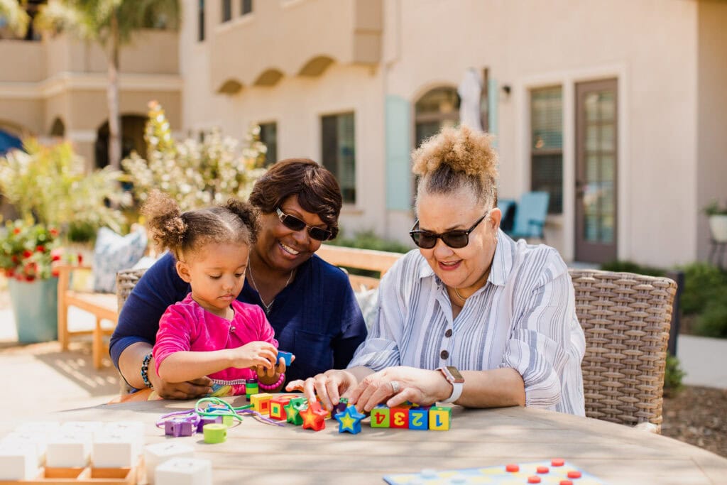 mother, grandmother, and young girl playing a game together