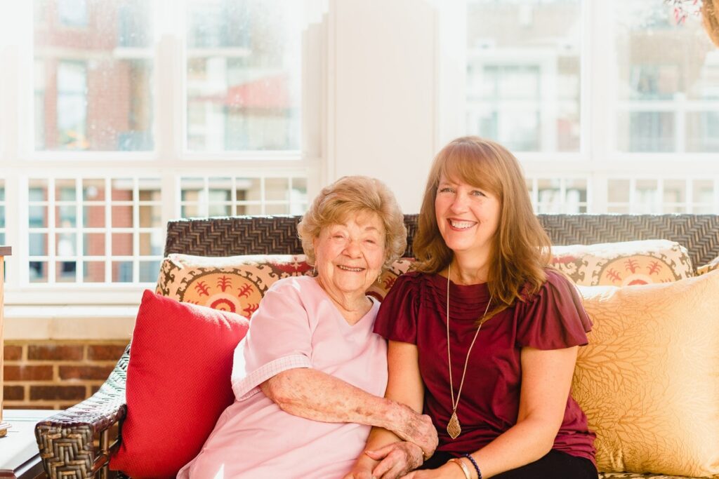 an elderly woman sitting with a female senior living team member